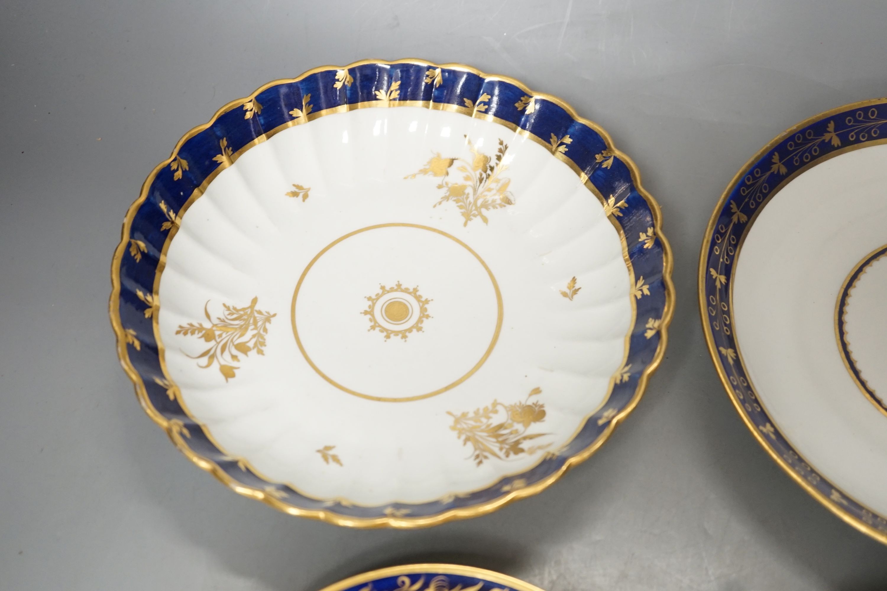 A Flight Barr and Barr teacup and saucer printed with shells, similar teacup and saucer with blue and gold decoration, and two Flight Barr and Barr gold and blue saucers dishes c. 1820, dish 20 cms diameter.